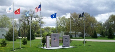 Flag poles and gray bench at Veterans park